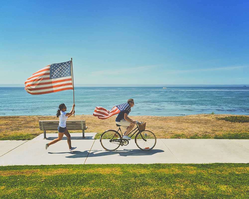 Man on Bike at Beach with Flag